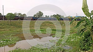 Outdoor scene with train wagons, pond and sky.