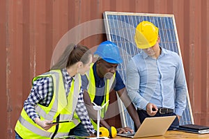 Outdoor shot of black African engineer inspect electrical solar panel wearing hardhat, protective eyeglass and safety equipment