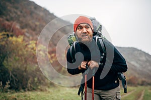 Outdoor shot of handsome Caucasian hiker young man hiking in mountains with travel backpack.