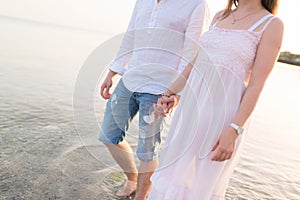 Outdoor shot of romantic young couple walking along the sea shore holding hands.