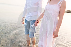 Outdoor shot of romantic young couple walking along the sea shore holding hands