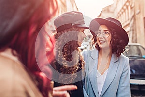 Outdoor shot of three stylish young women talking on city street. Friends laughing and having fun