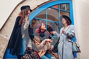 Outdoor shot of three young women chatting and laughing on city street. Best friends talking and having fun