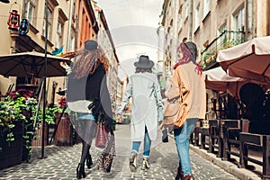 Outdoor shot of three young women walking on city street. Girls having fun. Back view