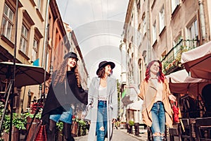 Outdoor shot of three young women walking on city street. Girls talking and having fun