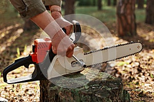 Outdoor shot of unknown person worker fixing chainsaw before or after deforestation, logger fixing tool for cutting trees,