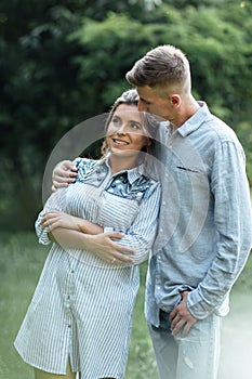 Outdoor shot of young happy couple in love on sunny day on nature. Man and woman hugging, sunlight in summer park. valentine`s da