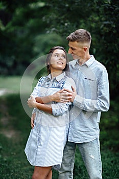 Outdoor shot of young happy couple in love on sunny day on nature. Man and woman hugging, sunlight in summer park. valentine`s da