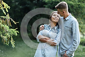 Outdoor shot of young happy couple in love on sunny day on nature. Man and woman hugging, sunlight in summer park. valentine`s da