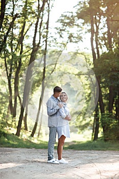 Outdoor shot of young happy couple in love on sunny day on nature. Man and woman hugging, sunlight in summer park. valentine`s da