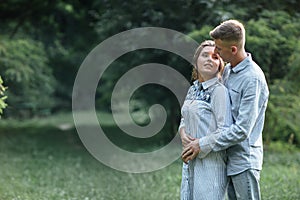 Outdoor shot of young happy couple in love on sunny day on nature. Man and woman hugging, sunlight in summer park. valentine`s da