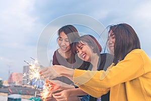 Outdoor shot of young people at rooftop party. Happy group of asia girl friends enjoy and play sparkler at roof top party.