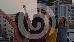 Outdoor shot of young people at rooftop party. Happy group of asia girl friends enjoy and play sparkler at roof top party at