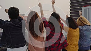 Outdoor shot of young people at rooftop party. Happy group of asian friends enjoy and play sparkler at roof top party at evening