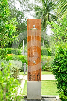 Outdoor shower head stick on the wooden plate pole design for showering body before jumping in the resort pool