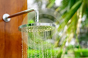 Outdoor shower head stick on the wooden plate pole design for showering body before jumping in the resort pool