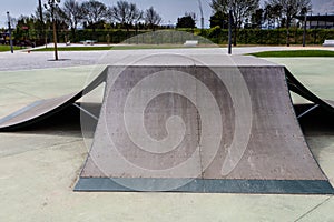 Outdoor skatepark with various ramps  with a cloudy sky