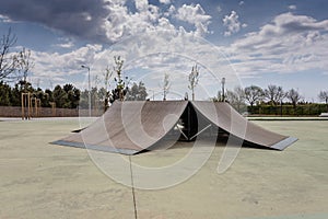 Outdoor skatepark with various ramps  with a cloudy sky