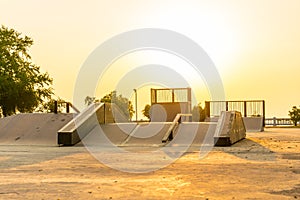 Outdoor skatepark with various ramps on sunset time