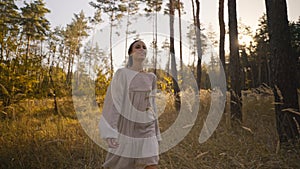 Outdoor slow motion video young beautiful girl in autumn landscape with dry wild flowers and tall grass. light white