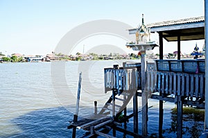 Outdoor spirit house on riverside local terrace in Thailand with garland and flowers in vases and some wreathes, joss house