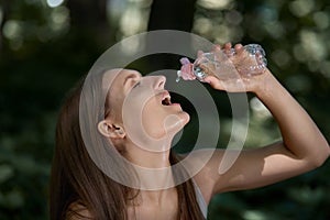 Outdoor sports. Young brunette woman quenches her thirst with water.