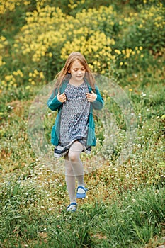 Outdoor spring portrait of cute 6-7 year old girl playing in yellow flowers field