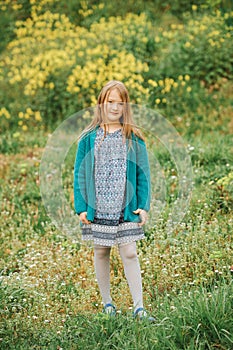 Outdoor spring portrait of cute 6-7 year old girl playing in yellow flowers field