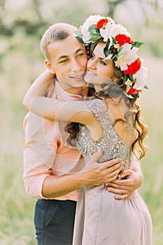 Outdoor spring portrait of young romantic hipster couple hugs posing, in the city garden around blooming trees and flowers