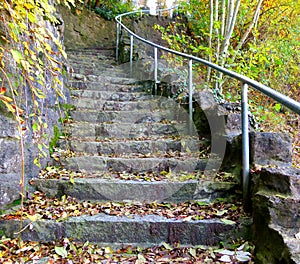 Outdoor staircase made of natural stones with a slight curve full of autumn leaves 2