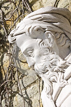 Outdoor stone statue of old man with beard and hat