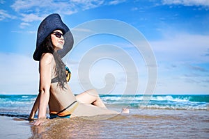 Outdoor summer portrait of Asian beautiful girl in a sexy bikini sitting on the beach in summer. teenage girls. sexy body. concept