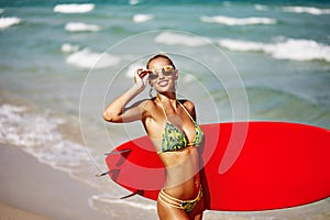 Outdoor summer portrait of slim beautiful woman with surfboard on a sunny beach