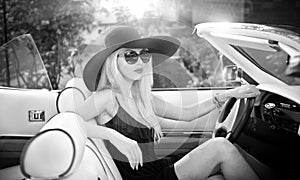 Outdoor summer portrait of stylish blonde vintage woman driving a convertible retro car
