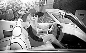 Outdoor summer portrait of stylish blonde vintage woman driving a convertible retro car. Fashionable attractive fair hair female