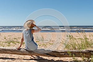 Outdoor summer portrait of a woman on the tropical beach looking out to sea, enjoying her freedom and fresh air, wearing a stylish