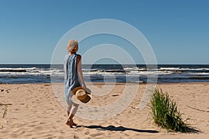 Outdoor summer portrait of a woman on the tropical beach looking out to sea, enjoying her freedom and fresh air, wearing a stylish