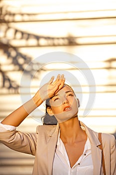 Outdoor summer portrait of young girl in suit suffering sun heat. Beautiful business woman at street in hot day.