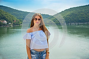 Outdoor summer portrait of young pretty long-haired brunette woman enjoying nature on mountain lake. Summer traveling, holiday.