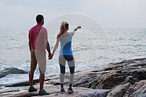 Outdoor summer portrait of young romantic couple in love posing at amazing stone beach,