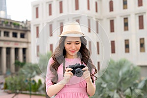 Outdoor summer smiling lifestyle portrait of pretty young woman having fun in the city in Asian with camera travel photo of