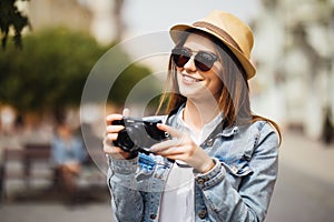 Outdoor summer smiling lifestyle portrait of pretty young woman having fun in the city in Europe in evening with camera travel pho