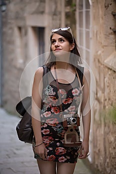 Outdoor summer smiling lifestyle portrait of pretty young woman having fun in the city in Europe with vintage analog camera. Woman