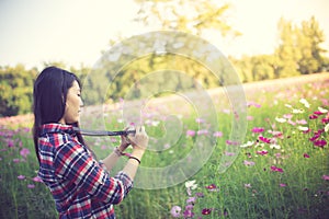 Outdoor summer smiling lifestyle portrait of pretty young woman having fun in the cosmos flower field with camera travel photo