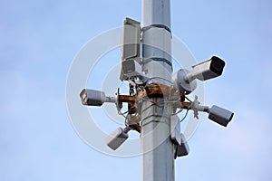 Outdoor surveillance video cameras on a concrete pole in blue sky