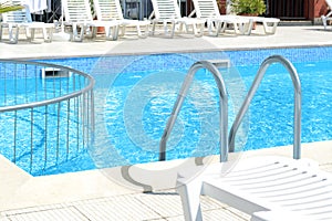 Outdoor swimming pool and loungers at resort sunny day