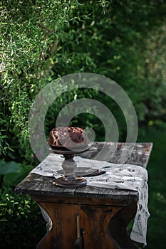 Outdoor table setting. Chocolate cake on a high wooden stand