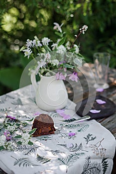 Outdoor table setting. Chocolate cake on a high wooden stand