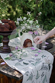 Outdoor table setting. Chocolate cake on a high wooden stand