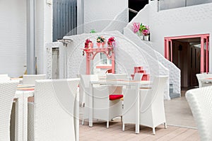 outdoor terrace of cozy restaurant with white wicker furniture.